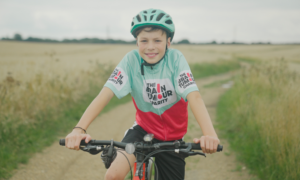 Harry Smith, posed on a bike in a Brain Tumour Charity t-shirt.